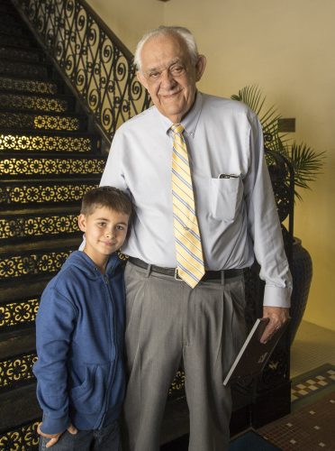 A boy and a man stand at the base of a staircase.