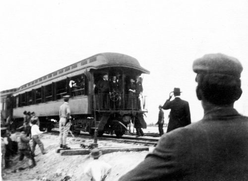 People on the back of a railroad car are viewed by others on the ground.