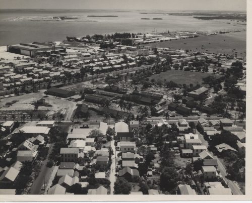 Aerial view of homes and a piece of open land along the waterfront.