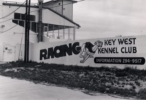 A wall next to a grandstand with an image of a greyhound reads Racing, Key West Kennel Club, Information 294-9517.