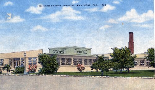 A colored postcard of a building with a sign that says Monroe County Hospital and text at the top that says Monroe County Hospital, Key West, F L A - K 26
