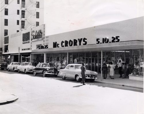 A store front with cars and people out front and a sign above that reads McCrorys and the numbers five, ten and twenty five.