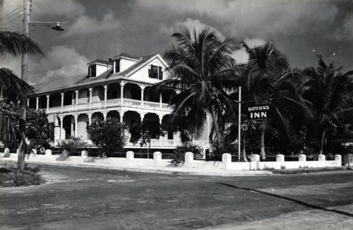 A three story building with palm trees and a sign out front that says North Beach Inn.