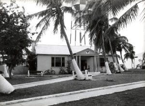 A building with palm trees in front and a water tower behind it.