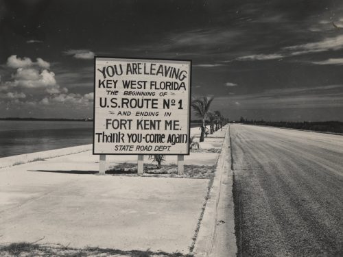 Sign reading "You Are Leaving Key West Florida, The Beginning of US Route No. 1 and Ending in Fort Kent Maine. Thank you, come again. State Road Department."