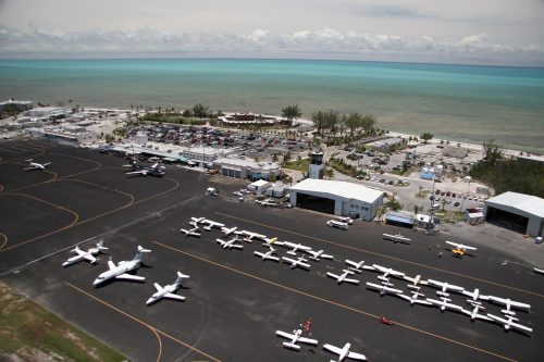 Aerial view of an airport with planes on the ramp and the ocean in the background.