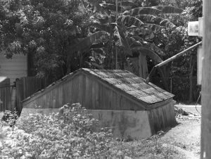 A small shed structure with a peaked roof and a pipe coming out of the top.