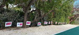 A row of placards along a tree line.