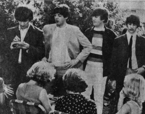 Four men in front with one man signing an autograph