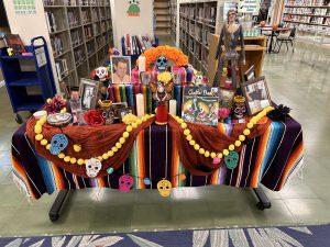 A table with skeletons and other symbols of the Day of the Dead, along with photos and other decorations.