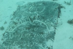 A grave stone underwater with a name and the words Died April 21, 1867, ae. 39 yrs.