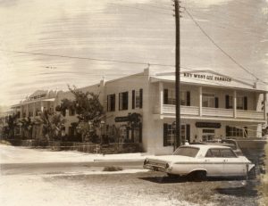 A large two story white building with signs that say Key West Hand Print Fabrics