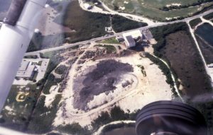 Aerial view of a landfill with a plane strut and wheel visible in the foreground.